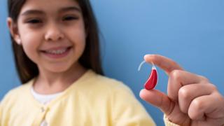 girl-holding-a-hearing-aid