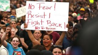An anti-racism protester holds a sign during the protest march