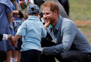 A young boy stroking Prince Harry's beard