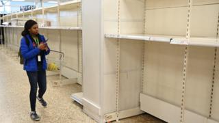 Shopper looks at supermarket shelves left empty after panic buying of toilet rolls