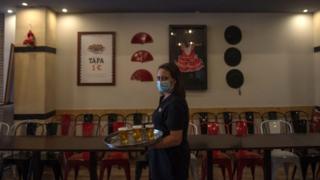 A waitress serves beer at a bar in Seville on 17 May 2020