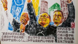 In this picture taken on September 25, 2018, local artist Fong So poses with two wood blocks which were used to make an artwork (R) at his studio in Hong Kong. - Illuminated under a spotlight at London's British Museum, hand-drawn sketches of Hong Kong's 2014 Umbrella Movement are part of a new exhibition on dissent that offers a rare glimpse of the artworks produced during the pro-democracy rallies.