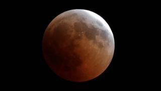 A "blood moon" rises during a lunar eclipse over Cairo, 27 July 2018