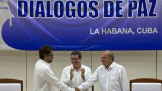 Uwuserukira reta ya Colombia mu biganiro Humberto de la Calle (i buryo) n'uwuserukira Farc Ivan Marquez (i bubamfu) bariko barashira umukono ku masezerano y'amahoro imbere y'umushikiranganji wa Cuba ajejwe imigenderanire Bruno Rodriguez