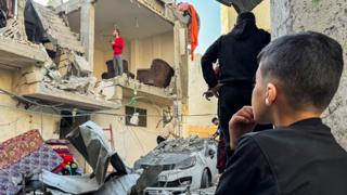 A Palestinian boy looks on as damage to a house is shown in the background in Khan Younis on 8 December.