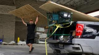 Man in New Orleans loads sheets of hardboard into his car, 23 August 2020