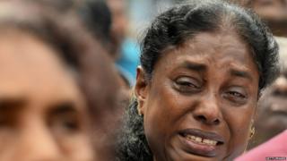 A Sri Lankan Christian devotee cries as she prays at a barricade near St. Anthony's Shrine in Colombo on