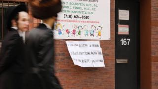 A sign placed outside the office of a doctor in New York warns people with measles to stay out of the way