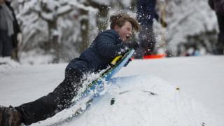 A boy tries to jump up a mound while sledding