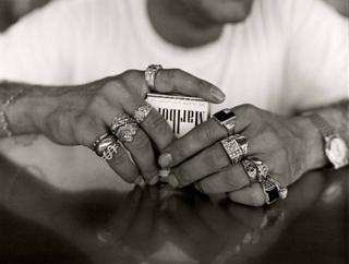 A man with lots of rings on his fingers clutches a packet of cigarettes
