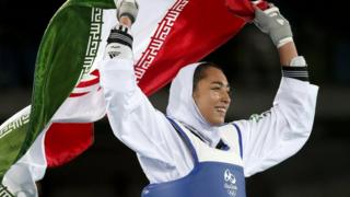 Kimia Alizadeh of Iran celebrates with the national flag after winning the women's -57kg bronze medal bout of the Rio 2016 Olympic Games Taekwondo event