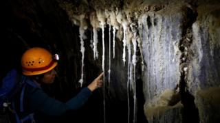 A woman looks at salt stalactites inside the Malham Cave in Israel