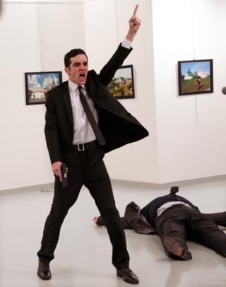 турецкий полицейский Мевлут Мерт Алтинтас с пистолетом в руке, через несколько секунд после того, как он застрелил посла