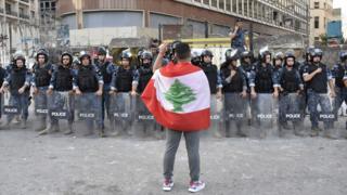 متظاهر يقف أمام القوى الأمنية في العاصمة اللبنانية بيروت، في يوليو/تموز 2020