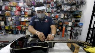 An employee cleans a guitar at a musical instruments store in Guadalajara, Jalisco State, on June 1, 2020 after Mexico began gradually reopening its economy after more than two months of shutdown because of the COVID-19 coronavirus pandemic