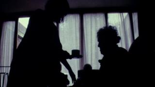 Neach-cùraim a' toirt cupa tì do chuideigin