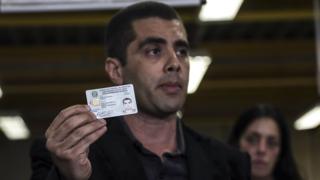 Fotografia de Denis Furtado, o Dr. Bumbum, segurando uma carteirinha do Conselho Federal de Medicina com sua foto