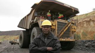 Man standing in front of a giant tipper truck at a diamond mine in Botswana