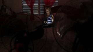Irma Arroyo reads a book with a flashlight at her home without power, after Hurricane Maria hit the island