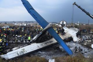 Непальские спасатели собираются вокруг обломков самолета, разбившегося около международного аэропорта в Катманду 12 марта 2018 года. По меньшей мере 40 человек погибли и 23 получили ранения, когда бангладешский самолет упал и загорелся возле аэропорта Катманду 12 марта в худшая авиационная катастрофа в Непале за последние годы. По словам официальных лиц, на борту самолета авиакомпании US-Bangla Airlines из Дакки находился 71 человек, когда он врезался в футбольное поле рядом с аэропортом