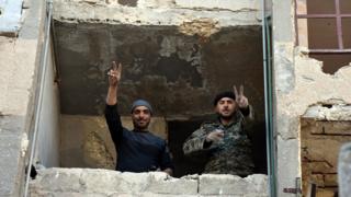 Syrian soldiers making a V for victory sign from a window of damaged building in Aleppo's eastern Masaken Hanano area in Aleppo province, Syria, 27 November