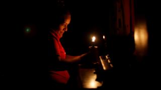 Una mujer se ilumina con una vela en Venezuela.