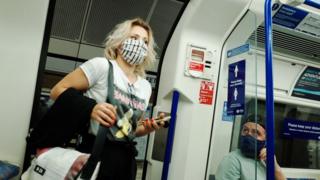 A woman wearing a face mask, currently mandated on public transport, boards a Northern line tube service at Warren Street station in London, England, on August 14, 2020.