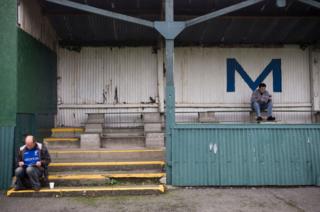 Two Matlock Town fans reading the matchday programme