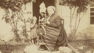 Woman and child at a spinning wheel