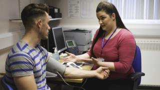 GP taking blood pressure of patient