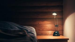 Lâmpada acesa ao lado da cama