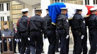 French police officers carry the flag-draped casket at the end of a ceremony honouring the policeman killed (pictured L) by a jihadist in an attack on the Champs Elysees, on 25 April 2017 at the Paris prefecture building