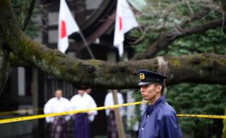 A police officer stands guard at Yasukuni shrine on the day of the bombing