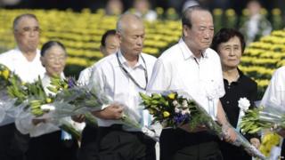 Attendees offer flowers for victims killed by the atomic bombing during the peace memorial ceremony marking the 70th anniversary of the nuclear bombing of the city at Hiroshima Peace Memorial Park (06 August 2015)