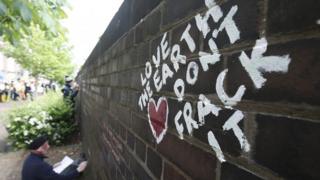 An anti-fracking protester writes messages on a wall in Lancashire