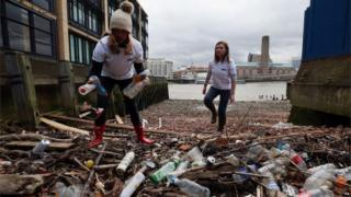 Волонтеры собирают и подсчитывают пластиковые бутылки на берегу реки Темзы в доке Куинхит в центре Лондона