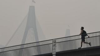 A man runs over a bridge during a smoky haze in Sydney on Tuesday