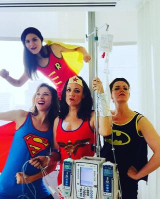Karen disfrazada como la Mujer Maravilla, rodeada de mujeres disfrazadas de Super Man, Batman y Robin.