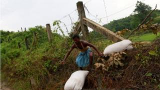 A Rohingya refugee crosses with his belongings over the Bangladesh-Myanmar border fence in Cox’s Bazar, Bangladesh,