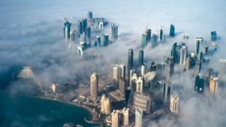 Аэрофотоснимок высотных зданий, возникающих в тумане, покрывающем горизонт Дохи
