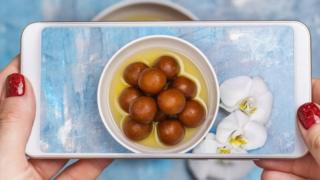 Žena fotografiše porciju gulab jamuna