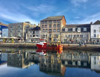 People and a boat reflected in water