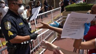 A police officer hands out unemployment benefit applications in a car park in Florida