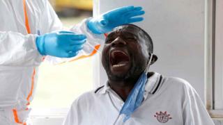 A Kenyan ministry of health medical worker takes a swab from a truck driver during a testing for the coronavirus disease (COVID-19), at the Namanga one stop border crossing point between Kenya and Tanzania, in Namanga, Kenya May 12, 2020.
