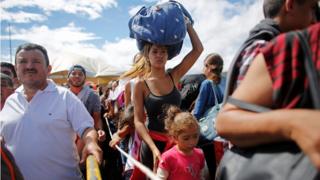 A woman carrying a bundle on her head wait in line to cross the border into Colombia from Venezuela on 17 July