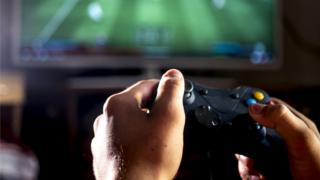 A gamer plays a football game on a TV