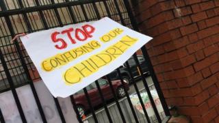 Знак «Хватит путать наших детей» на железных перилах возле школы