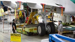 Workers stand beneath wing of 737 Max