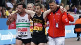 Matthew Rees ayuda a David Wyeth, junto a un oficial de la organización, a cruzar la meta en la maratón de Londrés