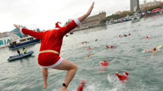 A participant in a Santa Claus costume jumps into the water during the 108th edition of the "Copa Nadal" (Christmas Cup) swimming competition in Barcelona's Port Vell on December 25, 2017